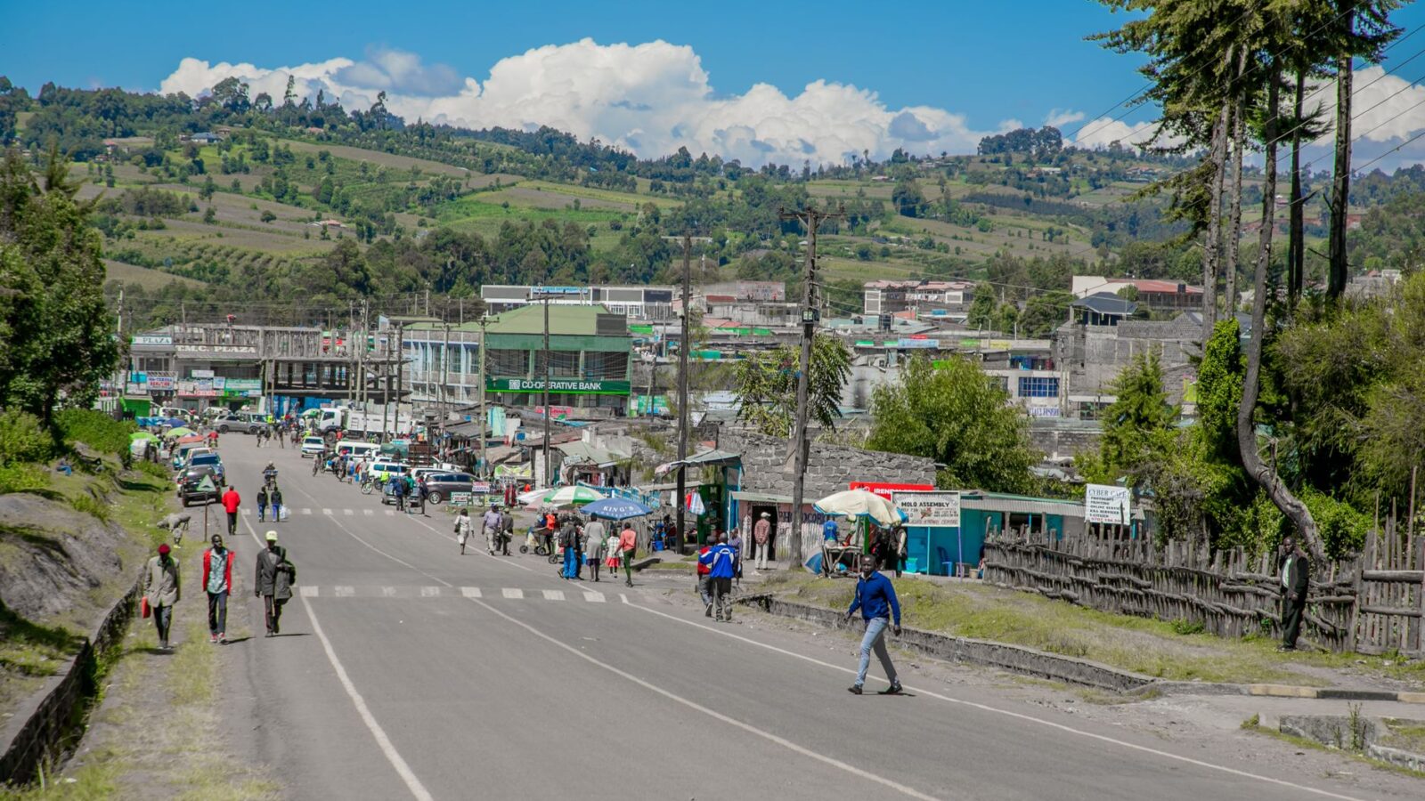 People walking on a busy street in a small African town on a sunny day.
