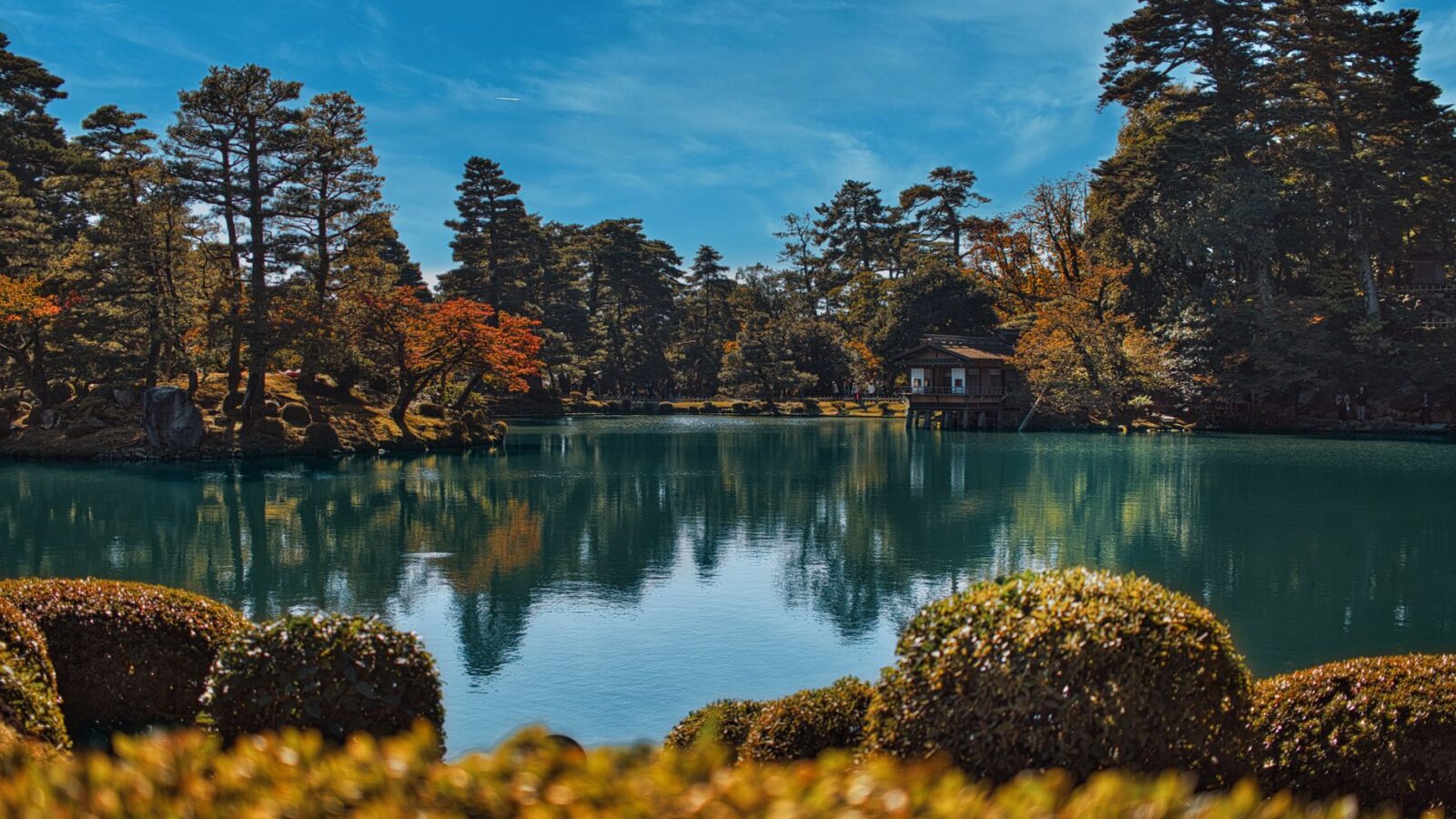 Capture the serene beauty of Kenrokuen Garden during autumn with tranquil waters and vibrant foliage.