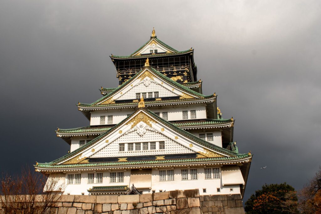 Stunning view of Osaka Castle with dramatic dark clouds. Iconic Japanese landmark.