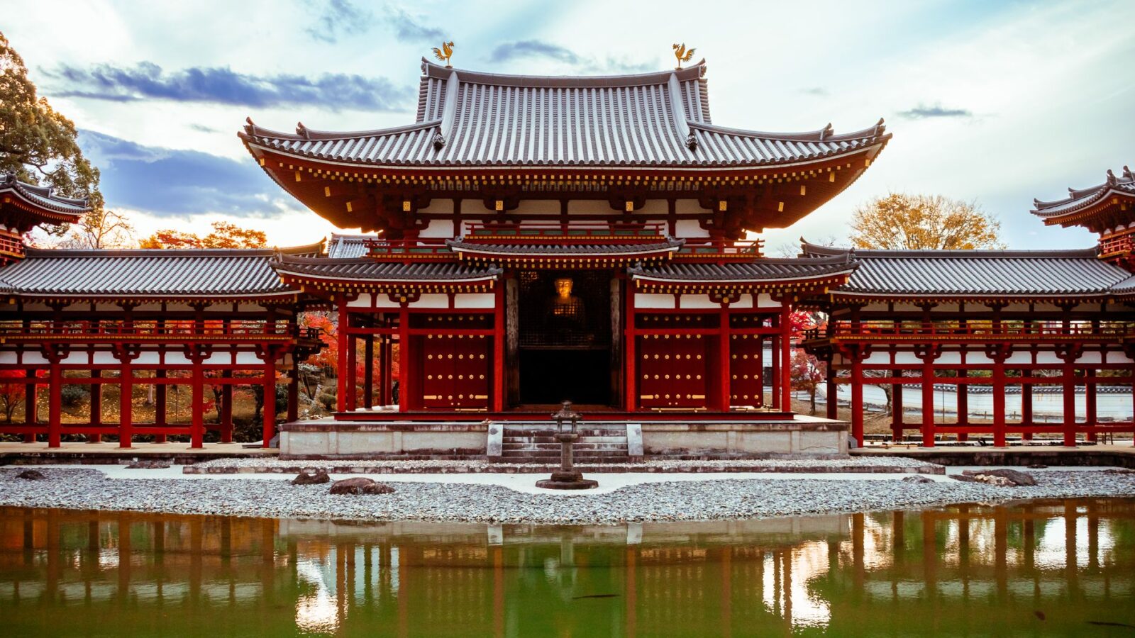 Historic Byodo-in Temple in Uji, Japan with autumn foliage reflecting in a serene pond.