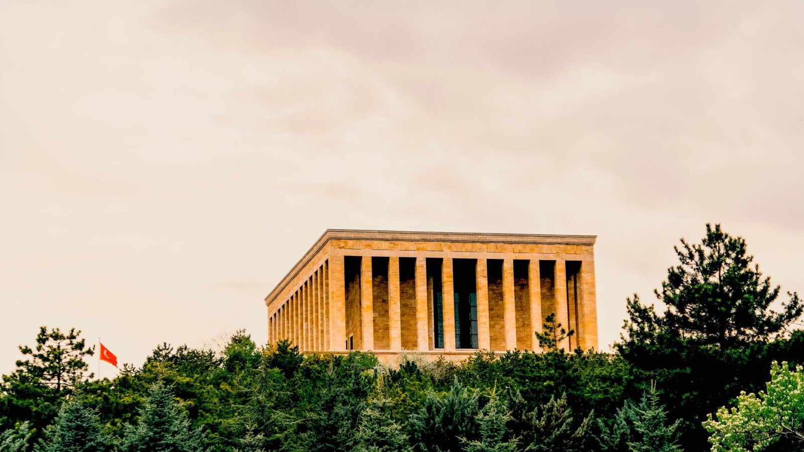 View of Anıtkabir in Ankara, Türkiye surrounded by lush greenery under a dramatic sky.