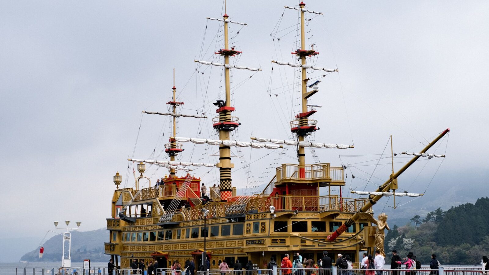Tourist crowds explore a replica pirate ship docked at Hakone's scenic lake.