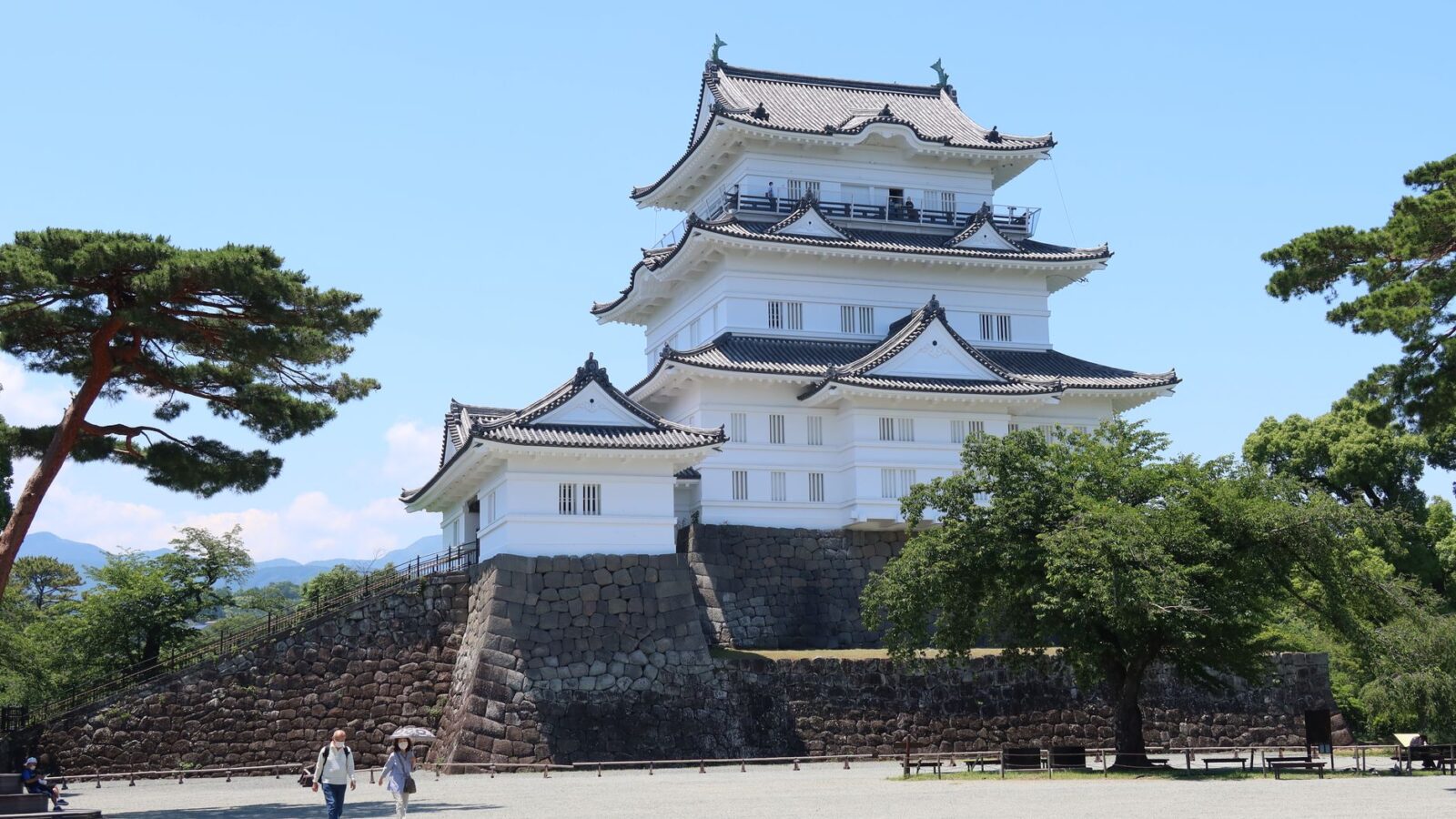 Beautiful Odawara Castle under a clear blue sky in summer, surrounded by lush greenery.